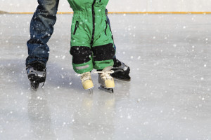 father and child learning to skate in winter snow