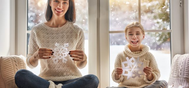 making paper snowflakes for decoration windows. Mother and child creating decorations.