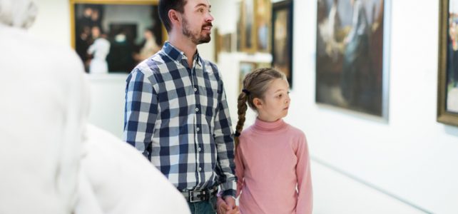 Glad young father and little daughter looking at expositions in museum